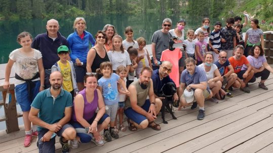 Foto di gruppo con Francesco in versione Avatar (maglietta arancione) davanti al Lago di Carezza
